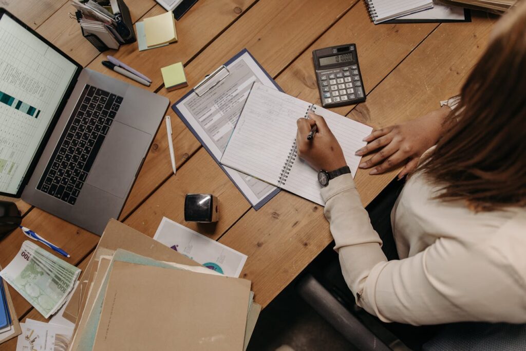 pexels-photo-7654585 Focused woman calculating figures at office desk with a laptop and documents.